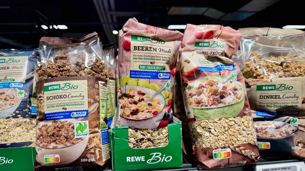 Mehrere Packungen des Müsli ohne Zuckerzusatz im Test in einem Verkaufsregal mit anderen Produkten.