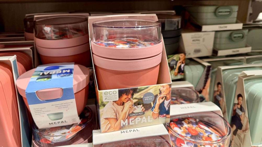 In einem Regal stehen mehrere Müsli-to-go-Becher im Test neben anderen Produkten.