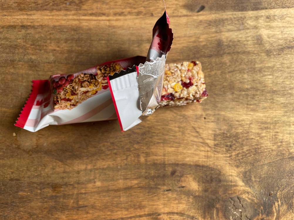 Auf einer Holzfläche liegt ein geöffneter Müsliriegel im Test.
