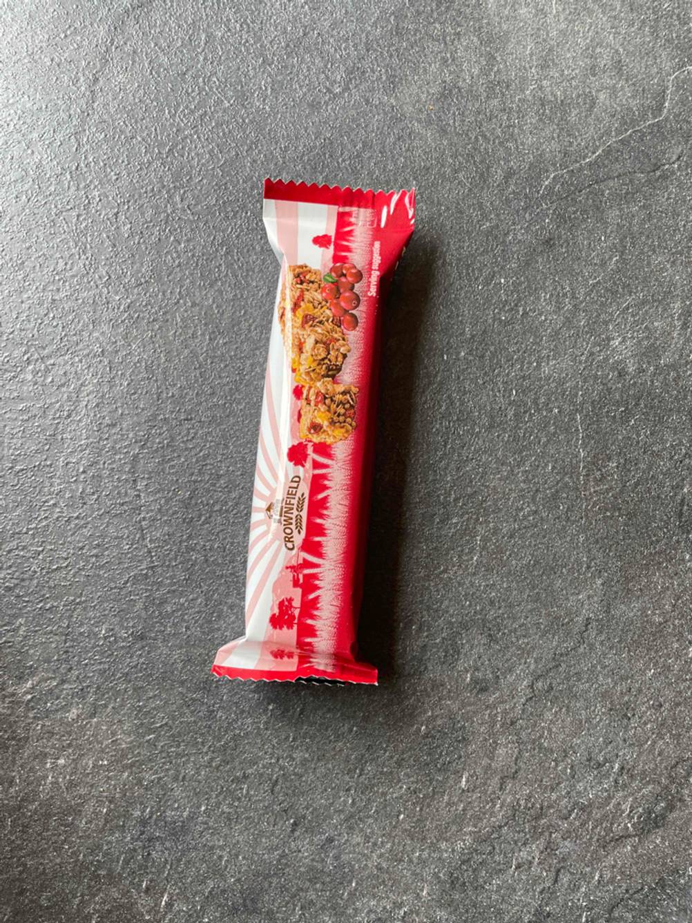 Ein einzeln verpackter Müsliriegel im Test auf einer dunklen Oberfläche.