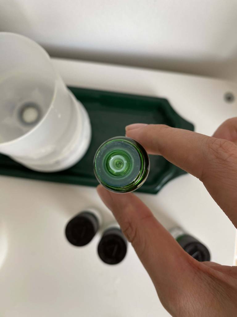 Aromatropfen getestet: Nahaufnahme des Dosierers von oben, eine Hand hält das Fläschchen hoch.