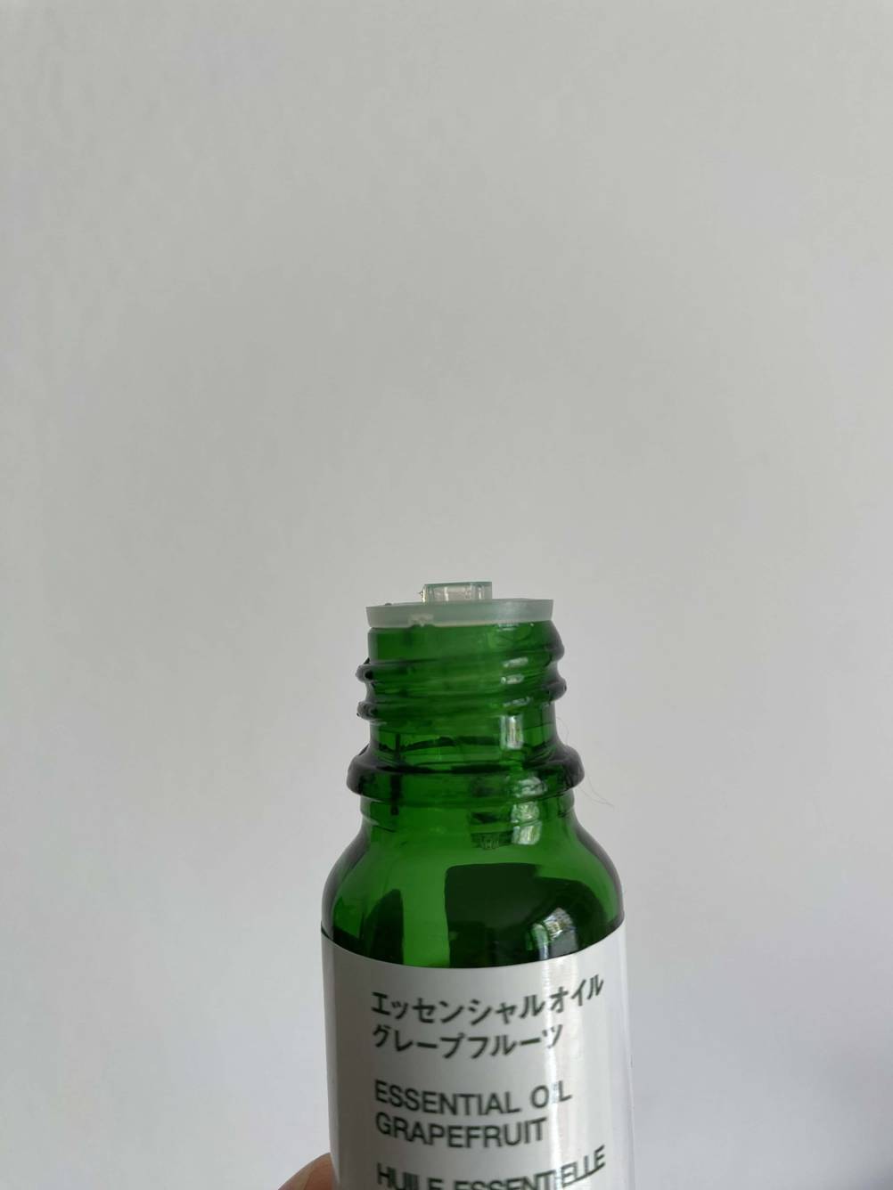 Nahaufnahme einer geöffneten Flasche Aromatropfen ohne Deckel vor einer hellen Wand.