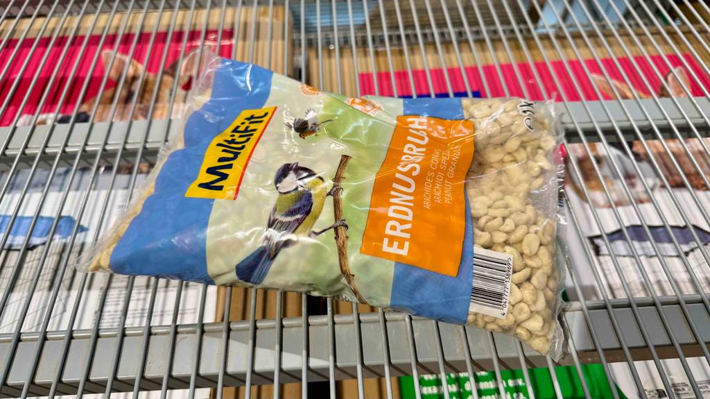 Eine Packung getestete Vogelfutter-Erdnüsse liegt quer in einem Gitterregal.