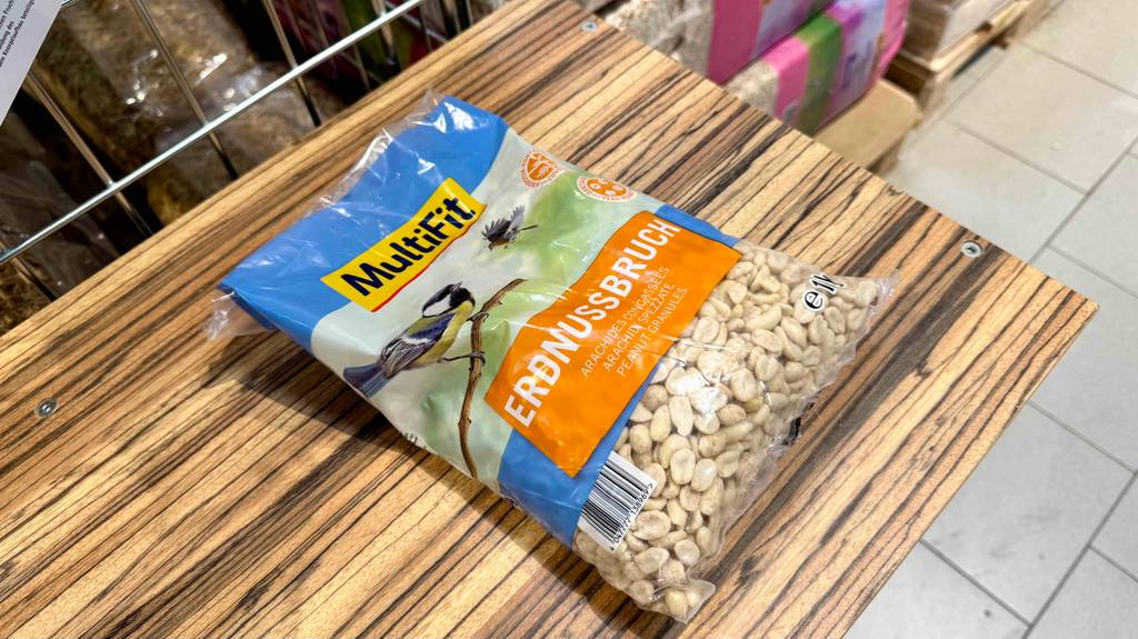 Eine Packung getestete Vogelfutter-Erdnüsse liegt auf einer Holzfläche.