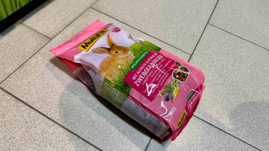 Eine Packung Zwergkaninchenfutter liegt zum testen auf einem hellen Fliesenboden.