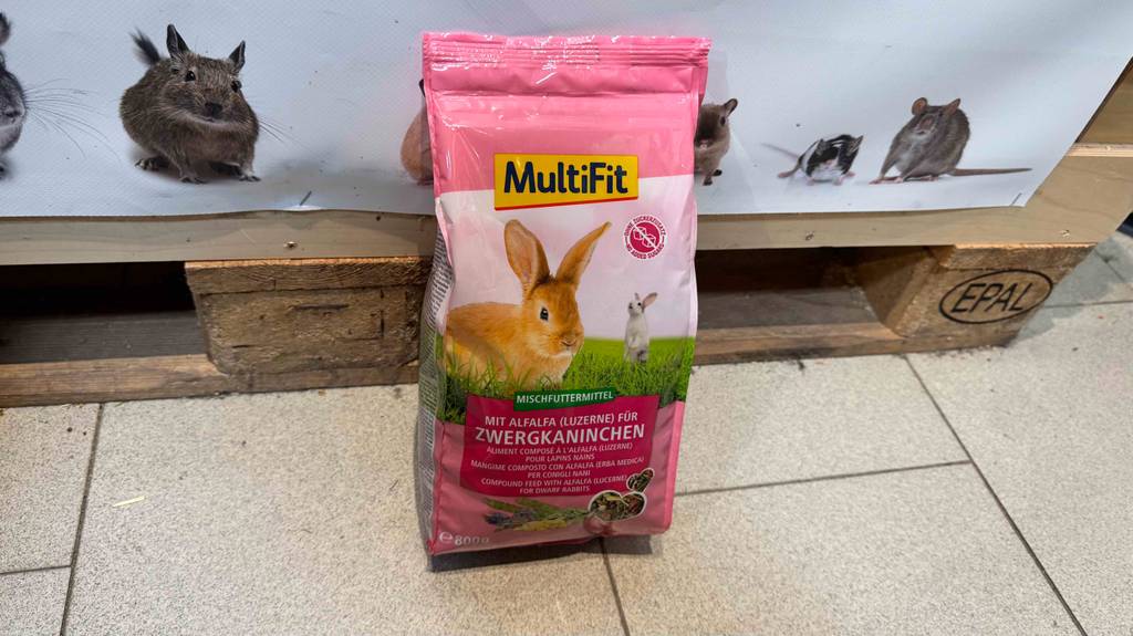 Eine Packung getestetes Zwergkaninchenfutter steht vor einem Plakat mit Nagetieren.