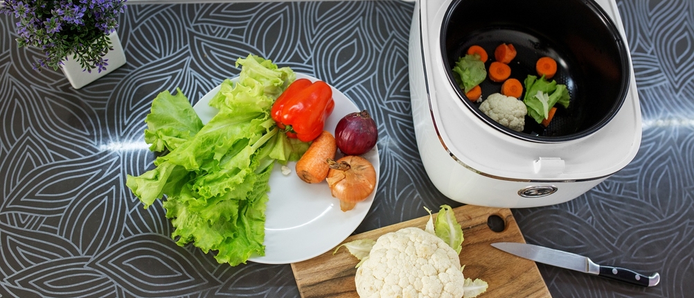 Multifunktionskocher mit Gemüse auf der Arbeitsplatte.