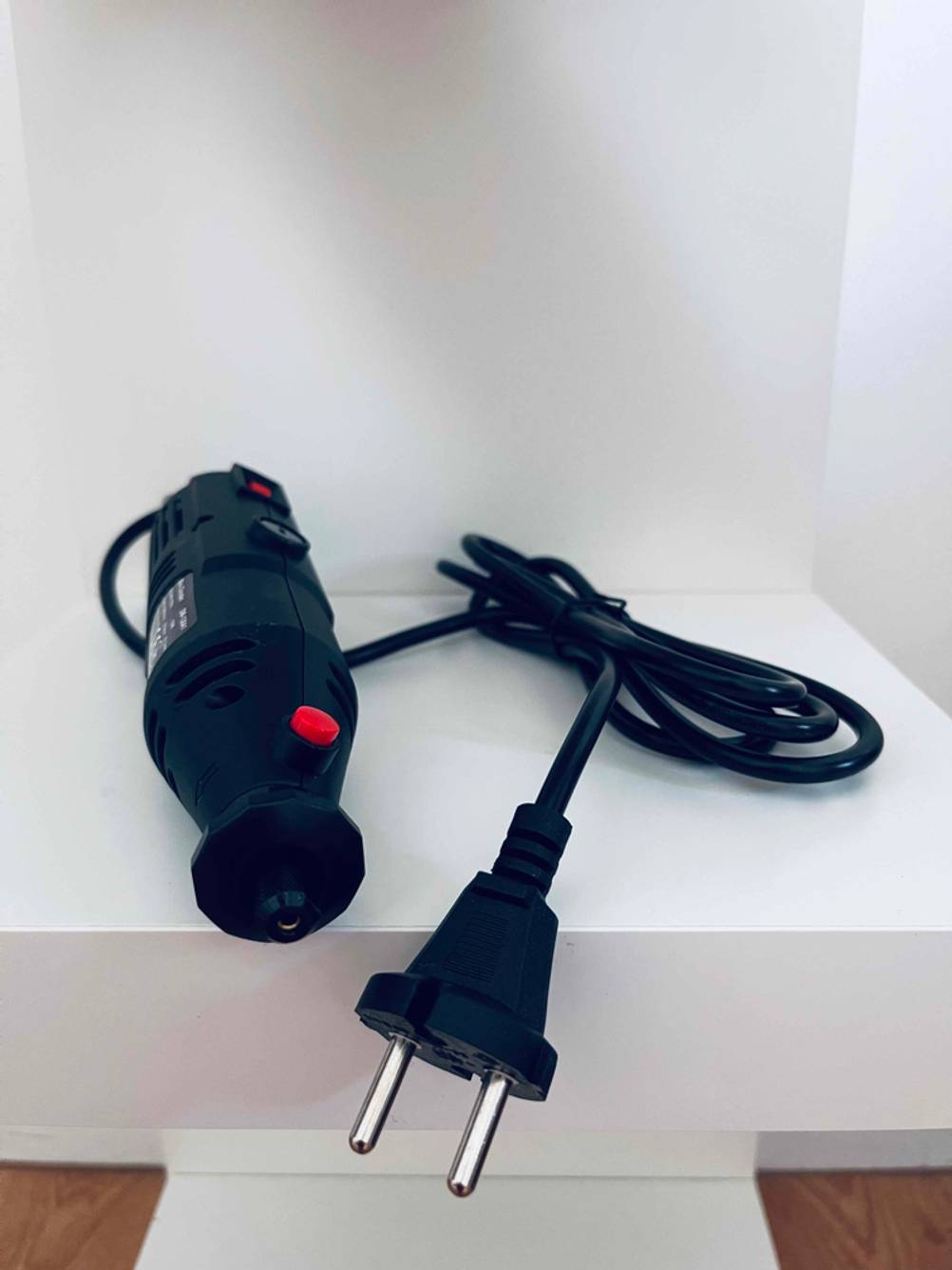 Multischleifer getestet: Ein Gerät auf einer hellen Fläche mit Fokus auf den Stromstecker.
