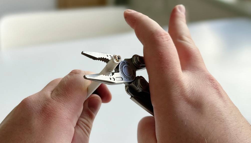 Zwei Hände nutzen das Leatherman Skeletool, um ein Kabel mit der Zange zu greifen. Eine Hand scheint dabei zu verkrampfen.