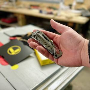 Das Leatherman Skeletool Multitool liegt zusammengeklappt in der Handfläche und zeigt die leichten Edelstahlgriffe mit markanten Aussparungen. Der Karabinerhaken am Griffende sorgt für eine einfache Befestigung.
