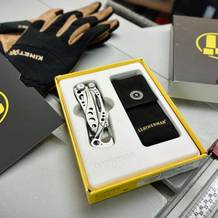 Das Leatherman Skeletool Multitool liegt in einer gelben Verpackung mit einem schwarzen Stoffholster daneben. Die stilvolle Kombination aus Edelstahl und schwarzem Griff ist gut sichtbar.