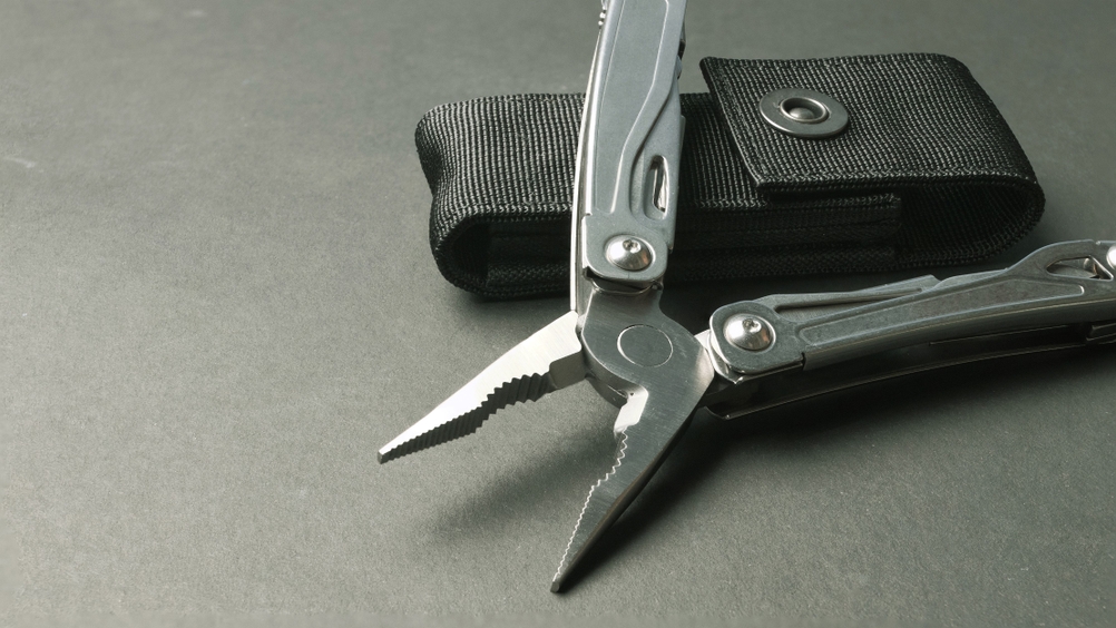Ein Multitool liegt neben seiner Gürteltasche