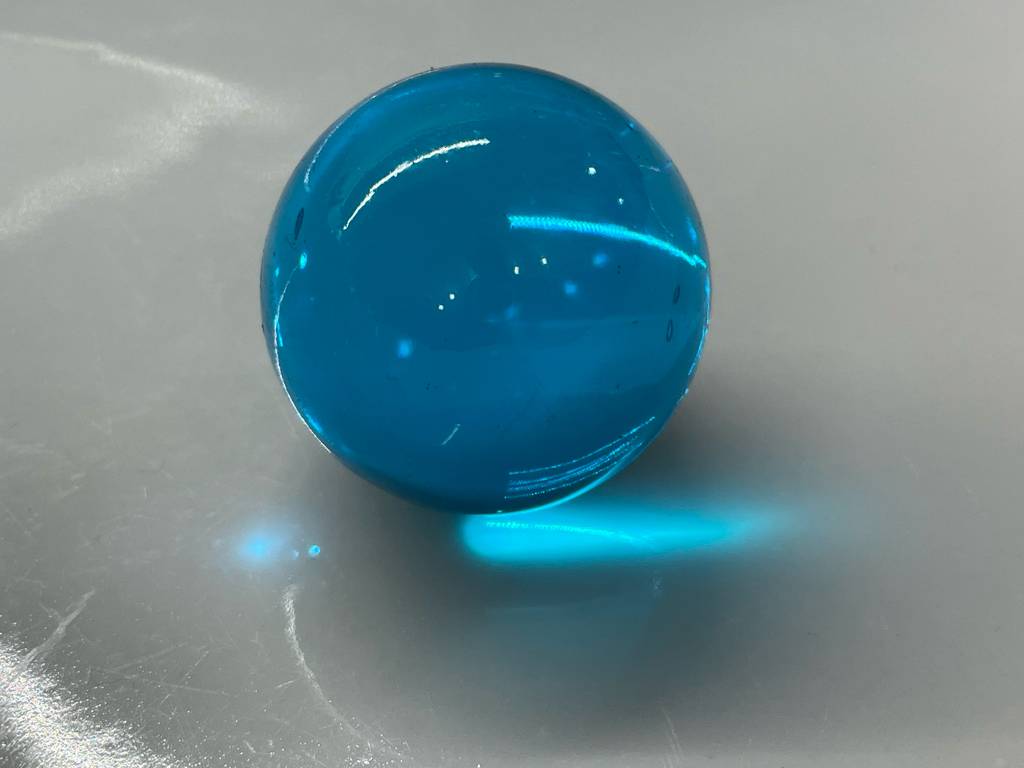 Murmeln-Test: Eine hellblaue transparente Murmel liegt auf einer weißen Fläche.