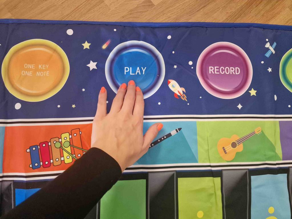 Musikmatte im Test: Eine Hand drückt auf die große Play-Taste.
