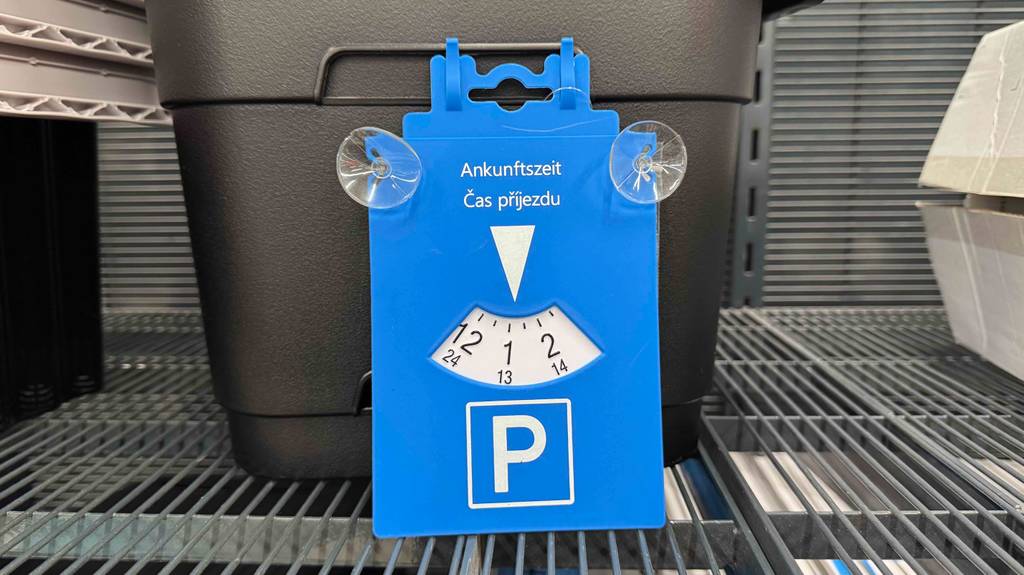 Parkscheiben im Test: Eine blaue Kunststoff-Parkscheibe mit Saugnäpfen lehnt an einem schwarzen Korb.
