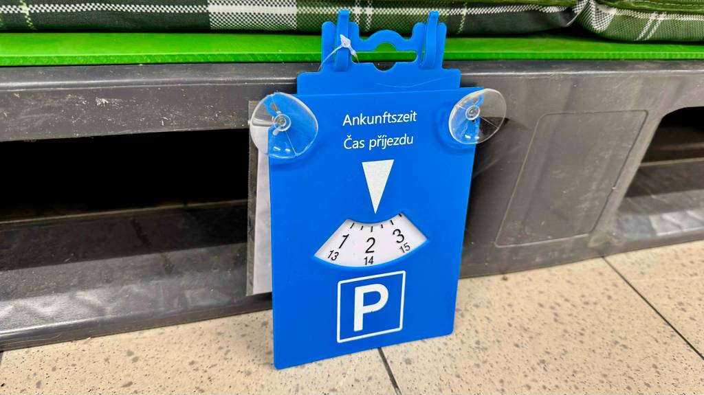Getestet: Eine Parkscheibe aus blauem Kunststoff inklusive zweier Saugnäpfe lehnt an einem Verkaufsregal.