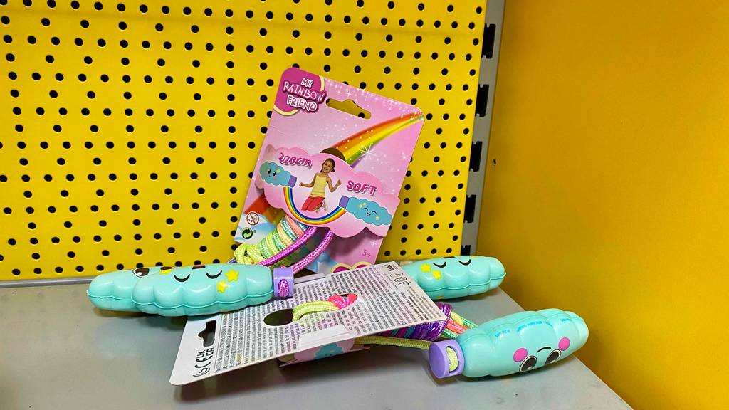 Zwei bunte getestete Springseile My Rainbow Friend mit Soft-Griffen befinden sich mit Blick auf Vorderseite und rückseitige Produktbeschreibung vor einer gelben Fläche.