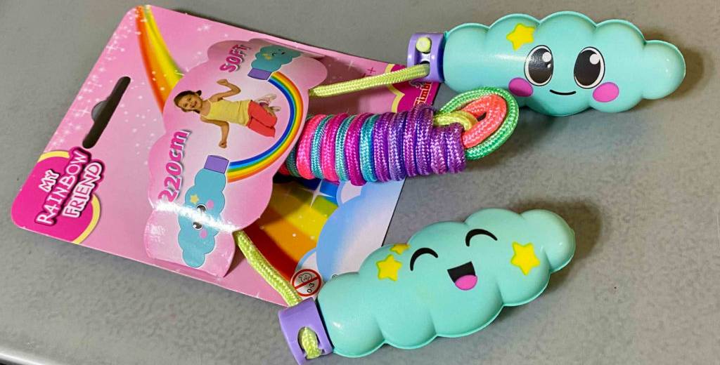 Springseil-Test: buntes My Rainbow Friend Kinderseil mit lustigen Gesichts-Griffen liegt auf grauem Untergrund.