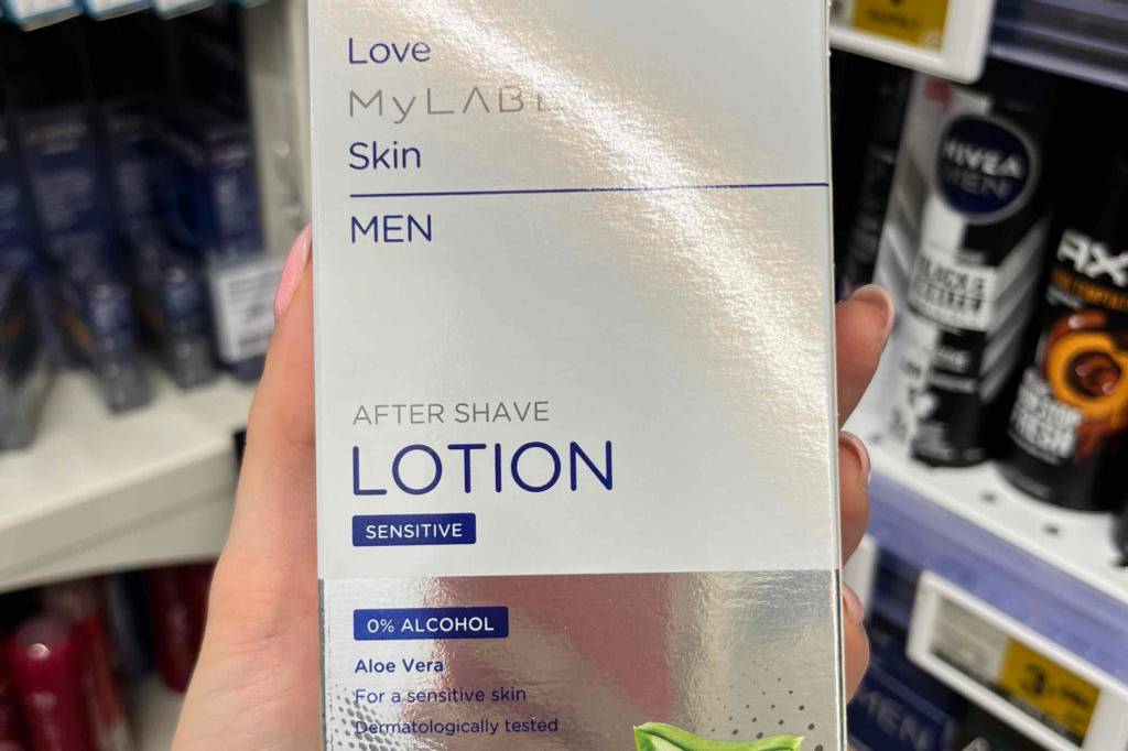 Im Test: Hand hält eine Packung Aftershave von My Label vor einem Regal.
