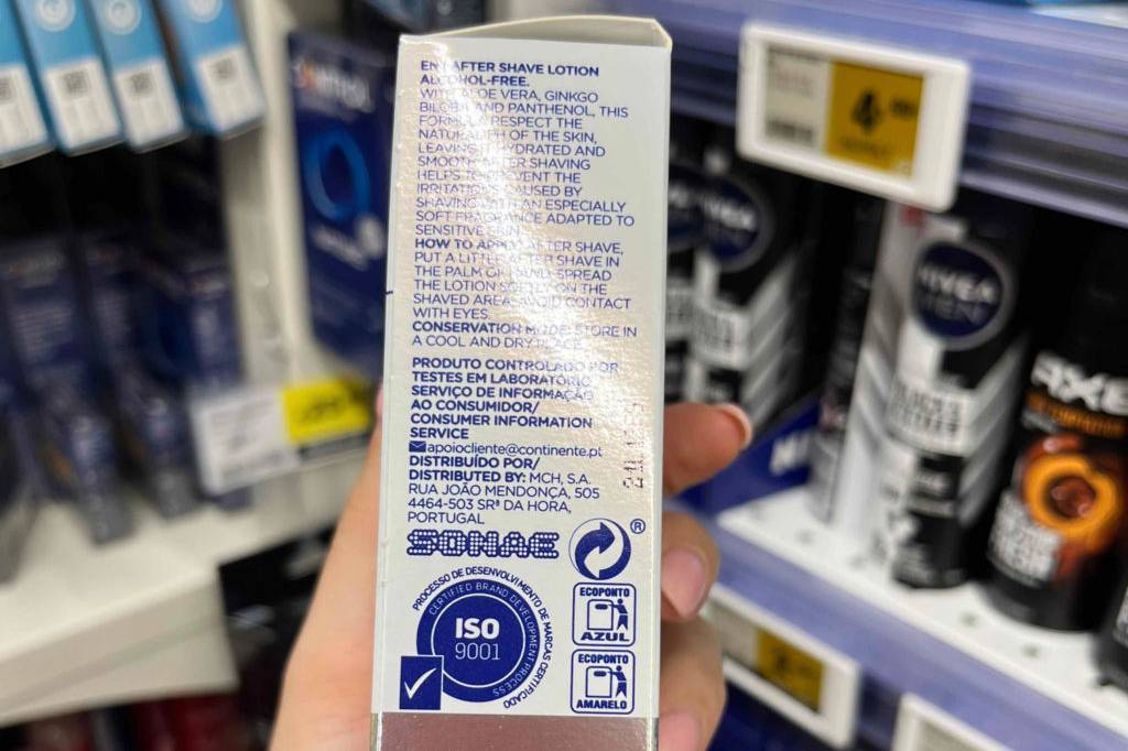 Im Test: Hand zeigt die Seite mit Inhaltsangaben einer Packung Aftershave von My Label vor einem Regal.