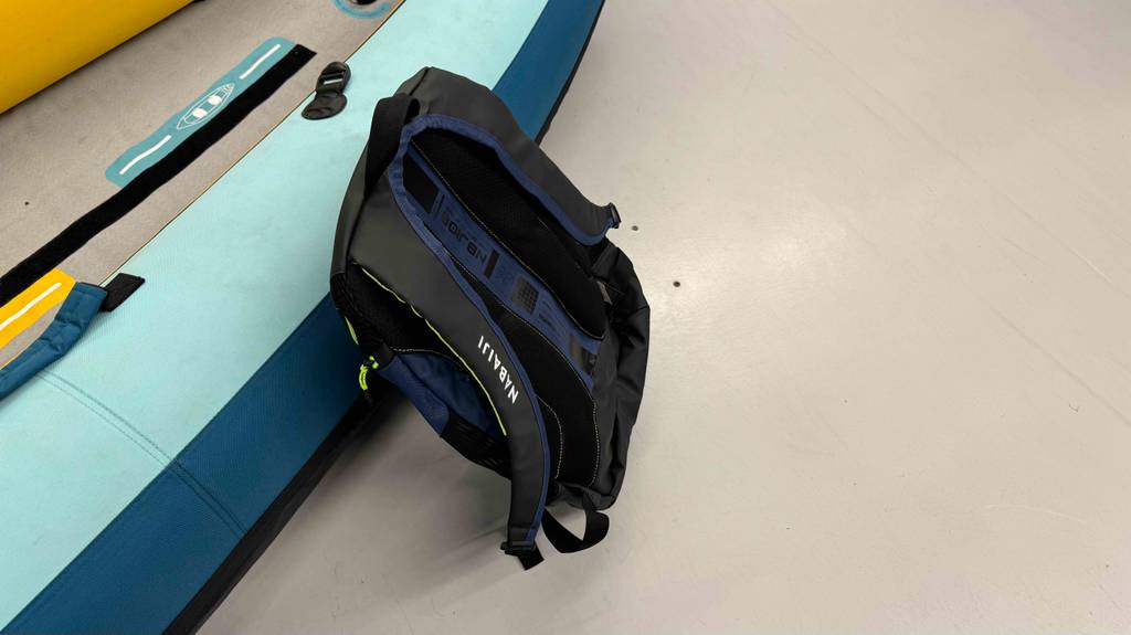 Der getestete Schwimmrucksack mit gepolsterten Schulterriemen lehnt an einem aufblasbaren Stand-up-Paddling Board.