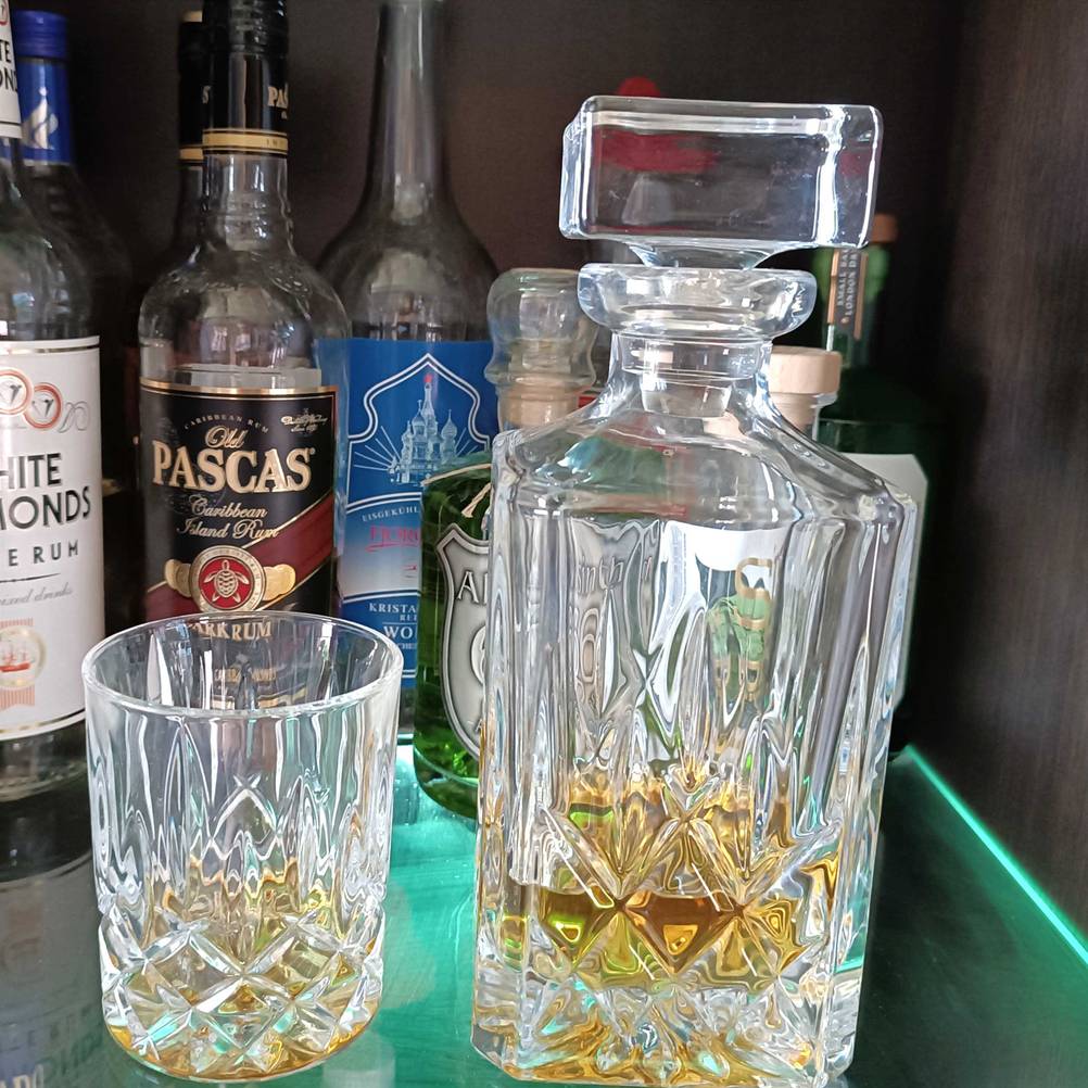 Getestet: Eine Whisky-Karaffe neben anderen Flaschen und einem Glas in einem Schrank.