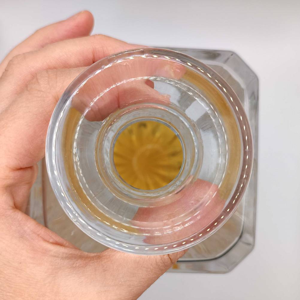 Nahaufnahme: Test einer Whisky-Karaffe von oben, die eine Hand hoch hält.