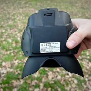 Unterseite des Bresser-Digital-NV-Binokulars mit einem Fokusrad zur manuellen Schärfeeinstellung. Eine Hand hält das Gerät, der Hintergrund ist unscharf.