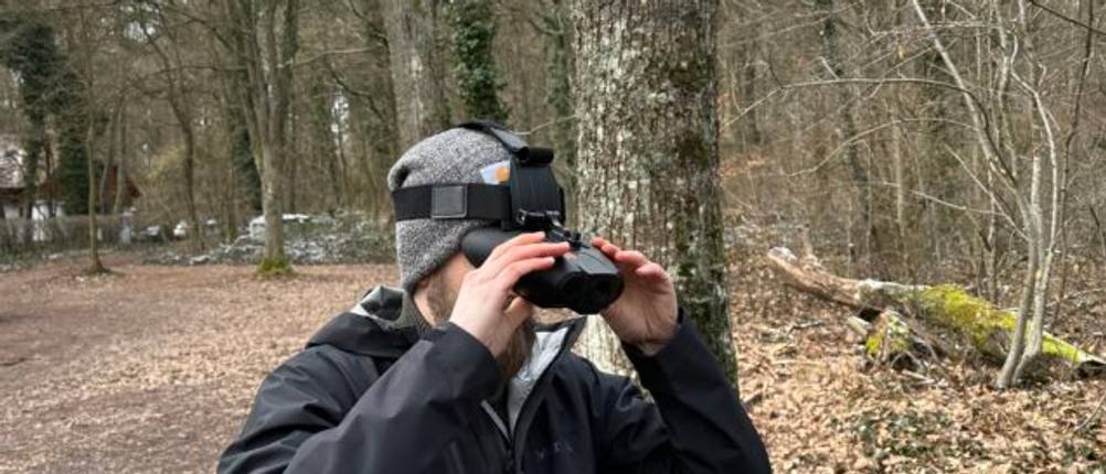 Das Nightfox-Swift-Nachtsichtgerät wird von einer Person mit Kopfhalterung getragen. Die Halterung sitzt sicher am Kopf, während das Gerät vor den Augen positioniert ist.