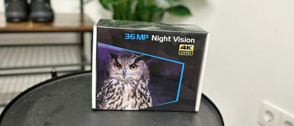 Die Verpackung des Relassy-NV4000-Nachtsichtgeräts steht auf einem Tisch, im Hintergrund sind Pflanzen und Schuhe zu sehen. Die Box zeigt eine Eule, 36 MP, 4K UHD und Night Vision.