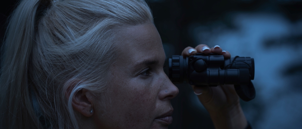 Eine Frau nutzt im Dunklen ein Nachtsichtgerät.