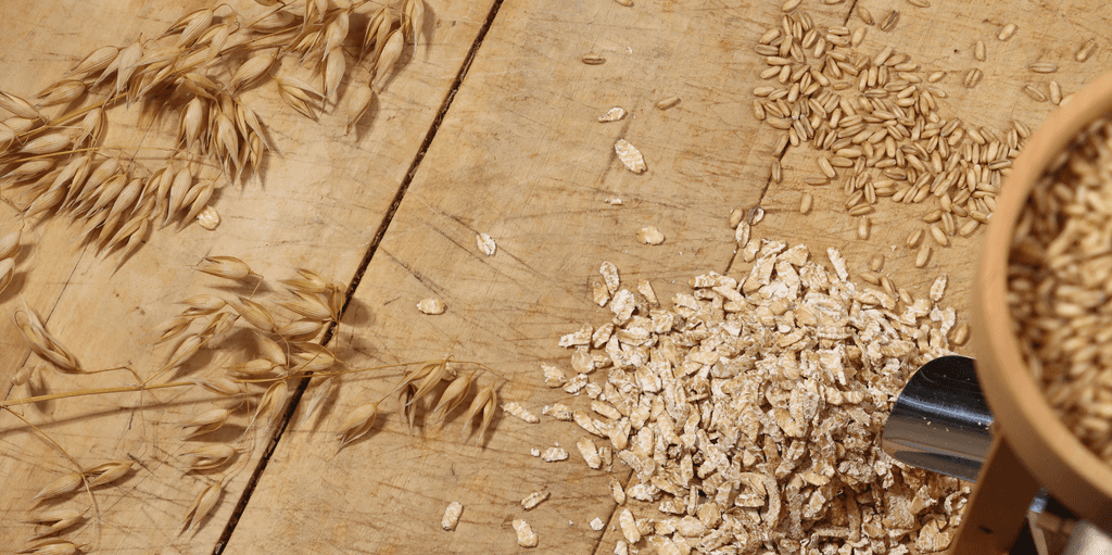 Nackthafer-Test: Nackthafer, Haferflocken und Haferzweige auf einem Holztisch.