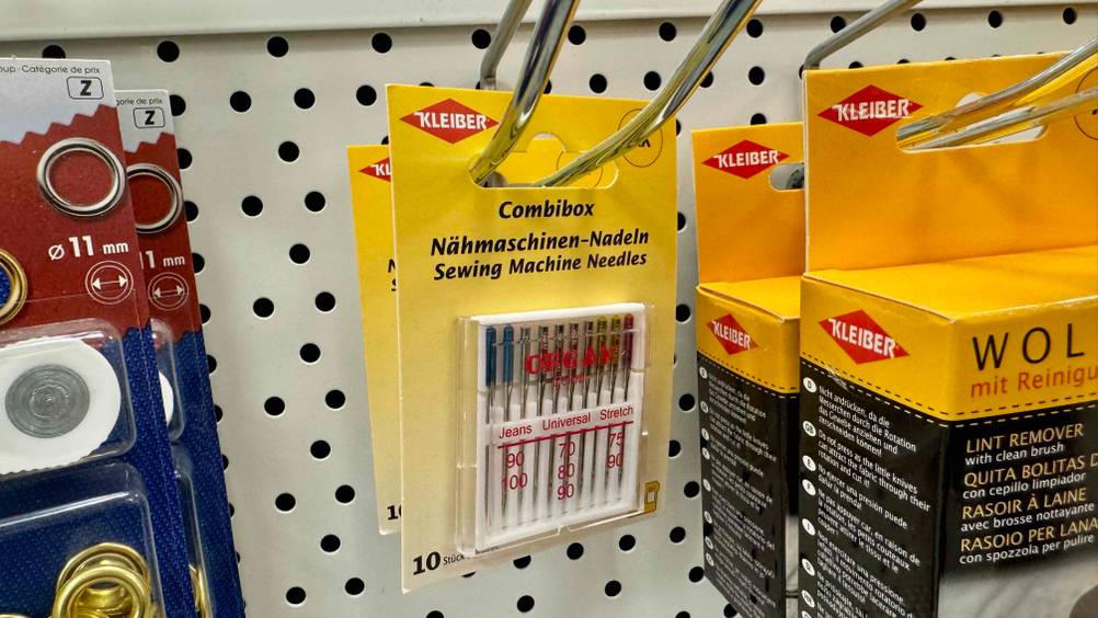 Mehrere Packungen der getesteten Nähmaschinennadeln in einem Verkaufsregal hängend.