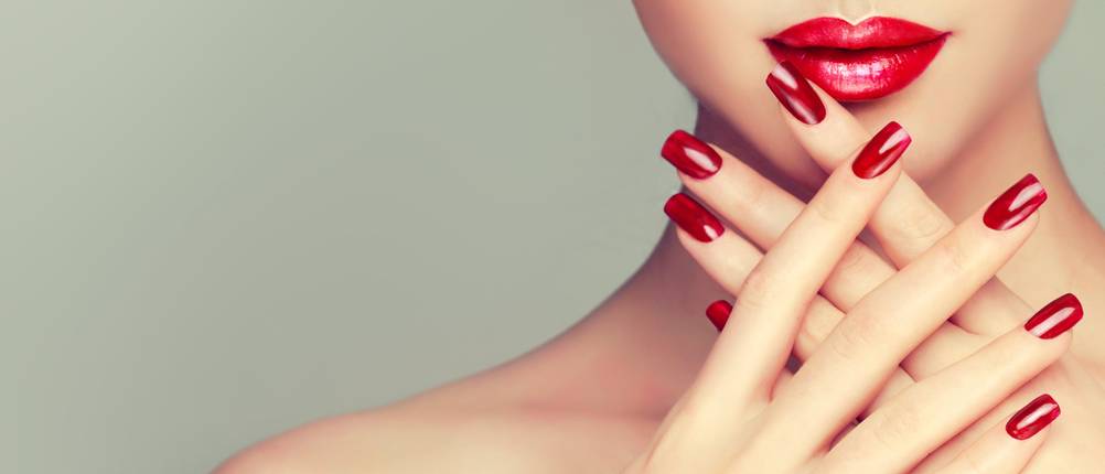 Beautiful girl showing red manicure nails . makeup and cosmetics