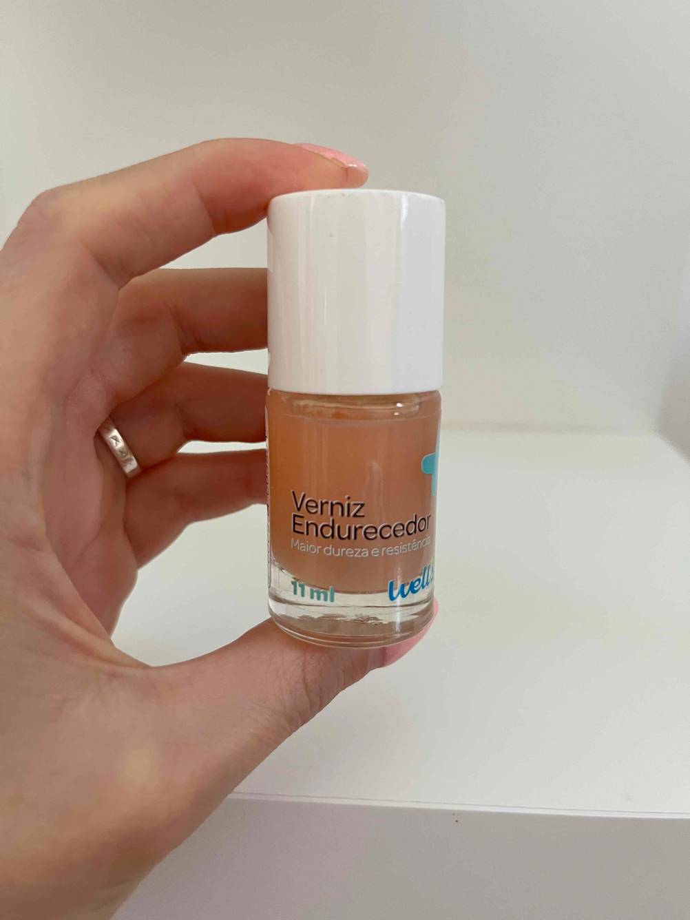 Eine Hand hält eine Flasche des Nagelhärters im Test vor eine helle Wand.