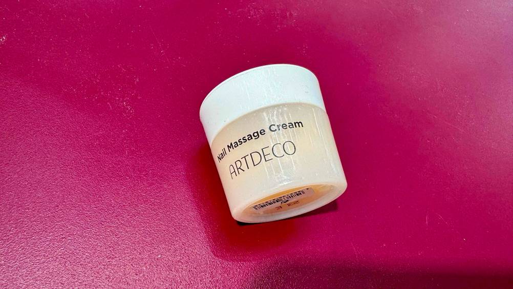 Nagelhautcreme im Test: Ein Tiegel auf einer roten Fläche.