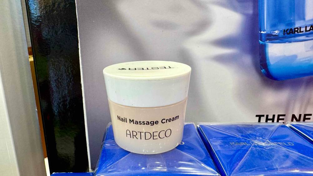 Auf einer blauen Verpackung steht der Tiegel der Nagelhautcreme im Test.