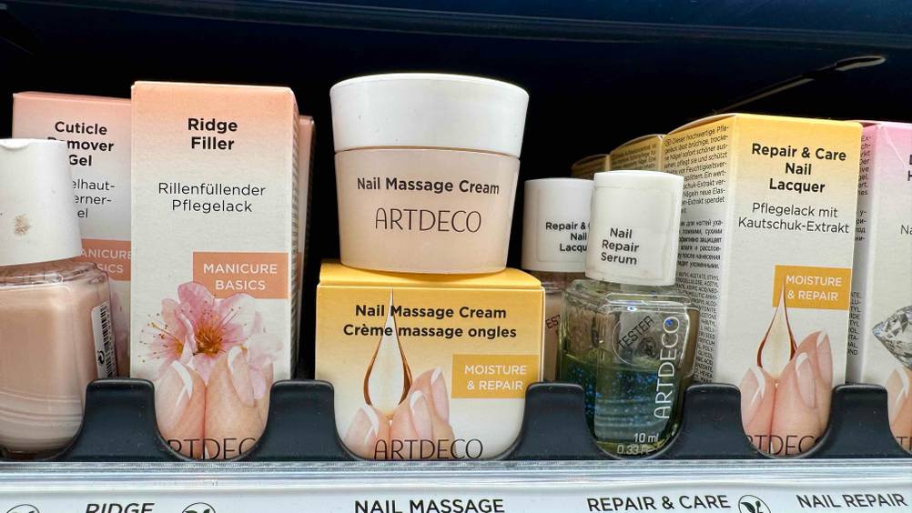 Auf der Originalverpackung steht ein Tiegel der getesteten Nagelhautcreme in einem Verkaufsregal.