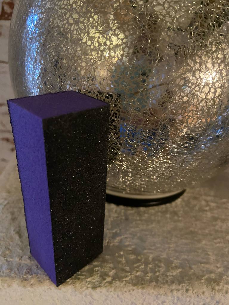 Im Test: Ein Nagelpolierblock steht mit Blick auf die Kanten vor einer Vase.