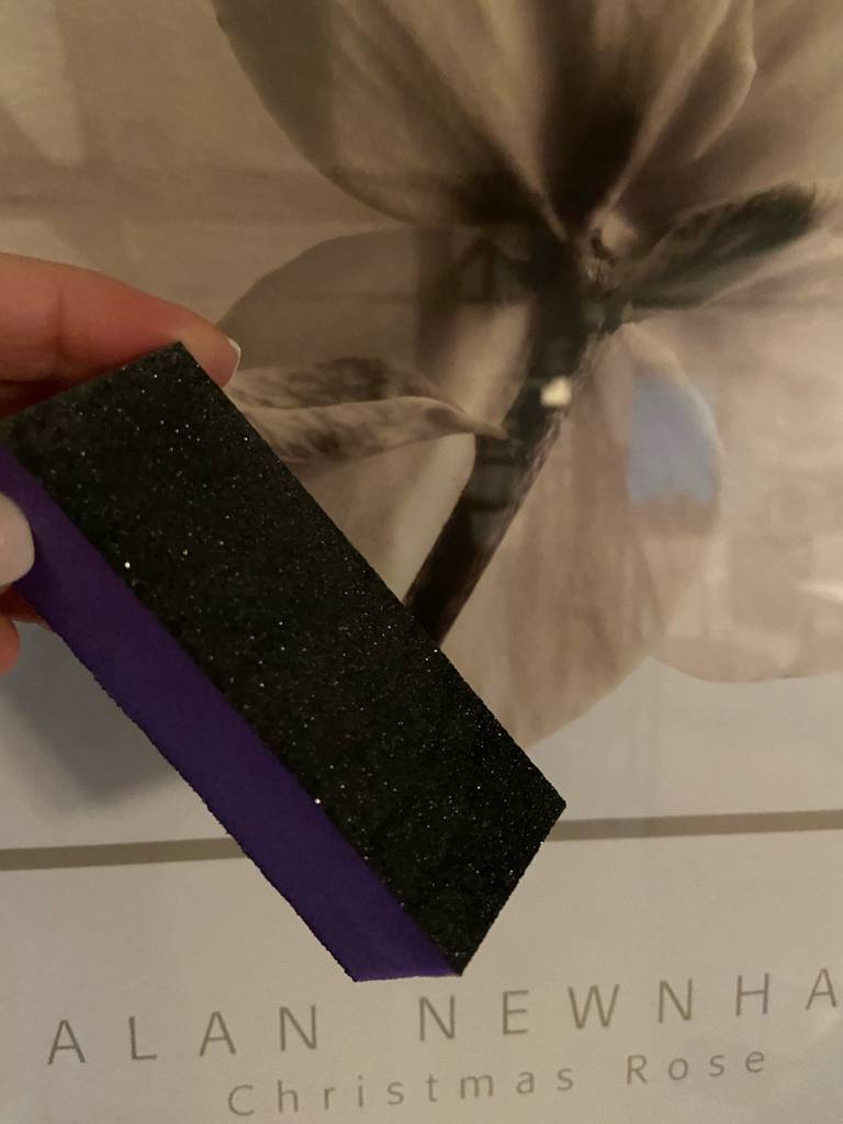 Im Test: Eine Hand hält einen Nagelpolierblock vor ein Blumenmuster.
