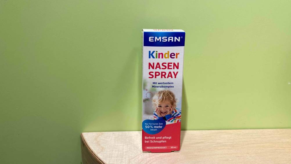 Im Test: Eine Packung Kindernasenspray von vorne vor einer grünen Wand.