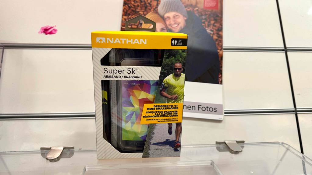 Ein Smartphone-Armband steht in Originalverpackung zum testen auf einem Glasregal.