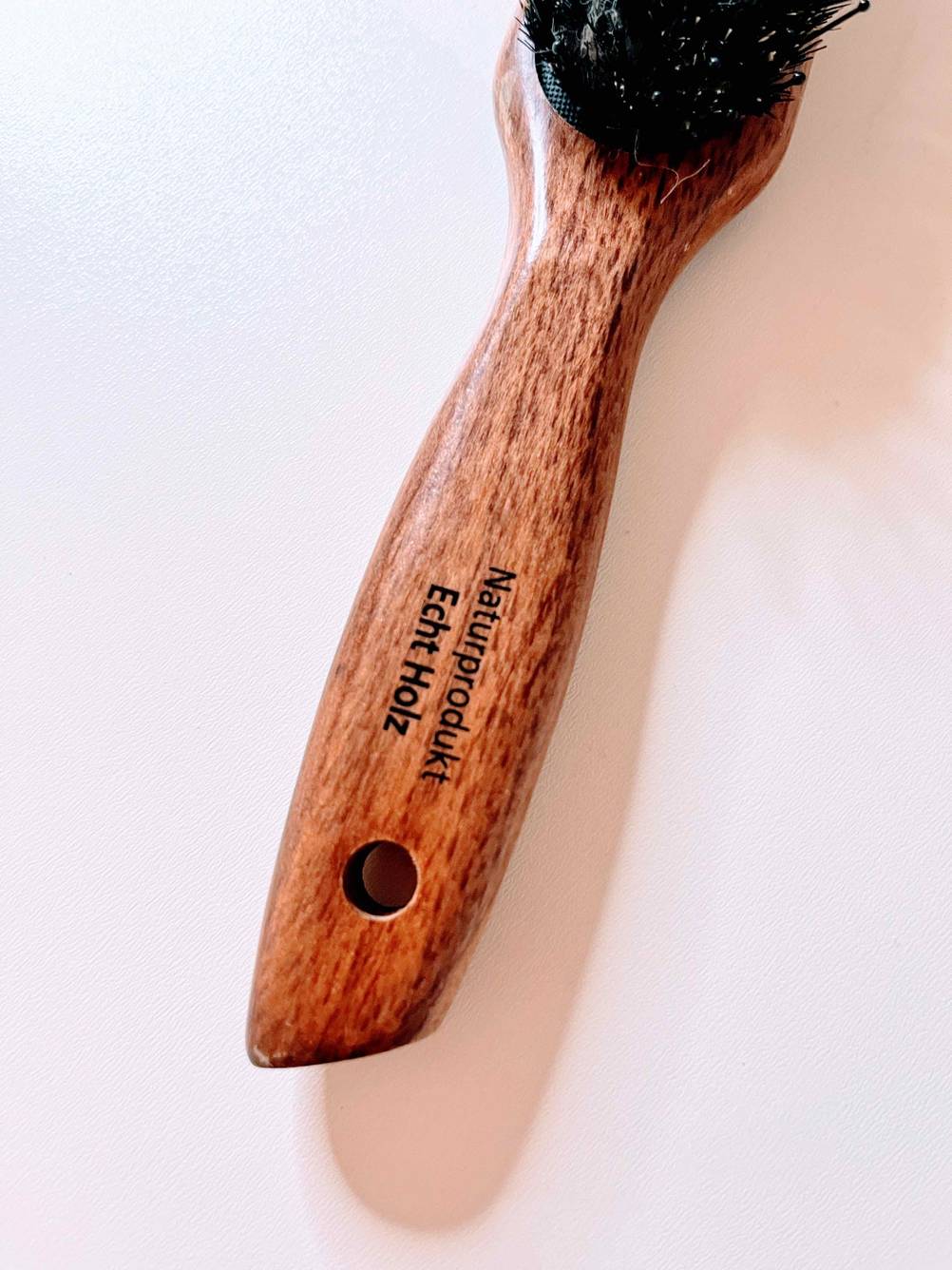 Stiel mit Hinweis auf Naturprodukt aus Holz einer getesteten Haarbürste mit Wildschweinborsten.