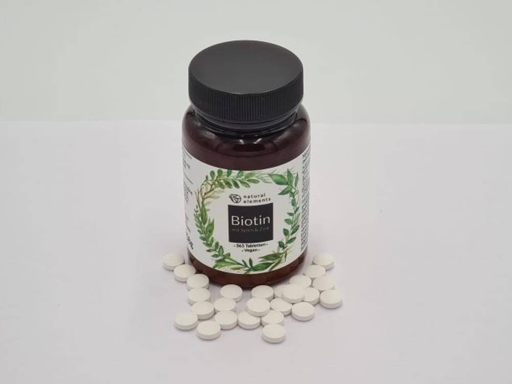 biotin-test: Auf einem Tisch steht Biotin in einer lichtgeschützen Dose. Um diese liegen mehrere Biotin-Tabletten.