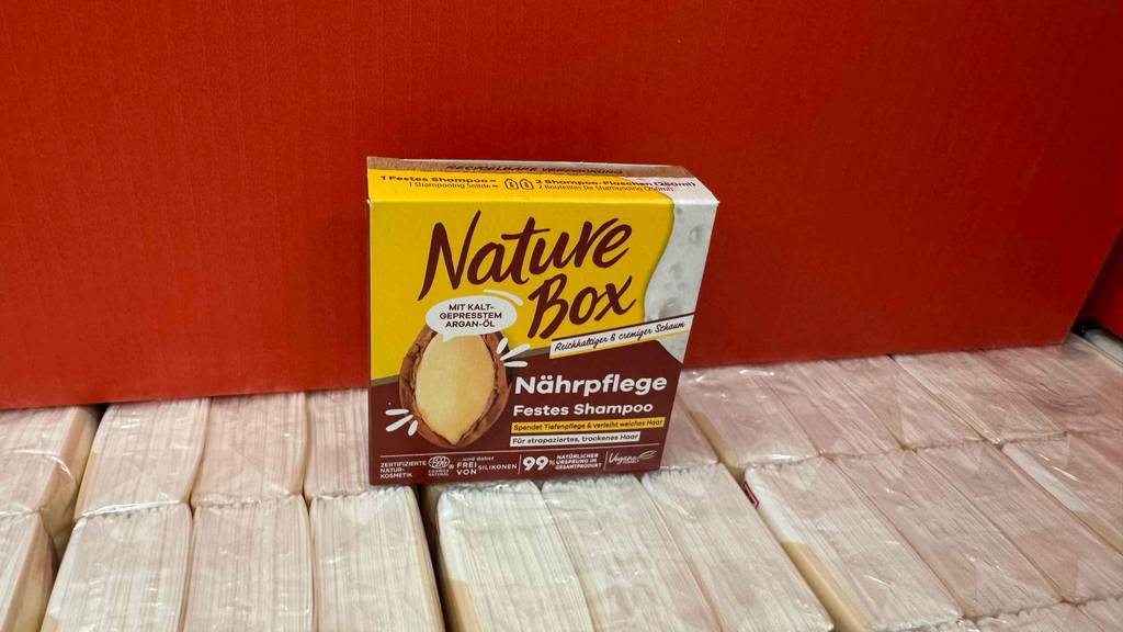 Eine Packung Nature Box festes Shampoo steht zum testen auf Taschentüchern.