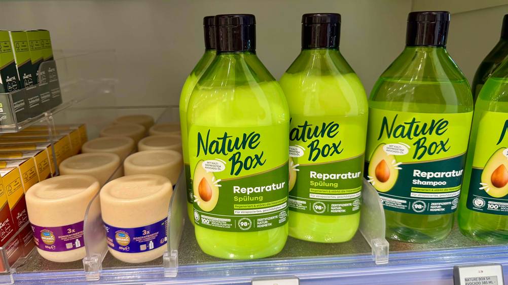 Mehrere Flaschen der getesteten Nature-Box-Spülung neben anderen Produkten in einem Regal.