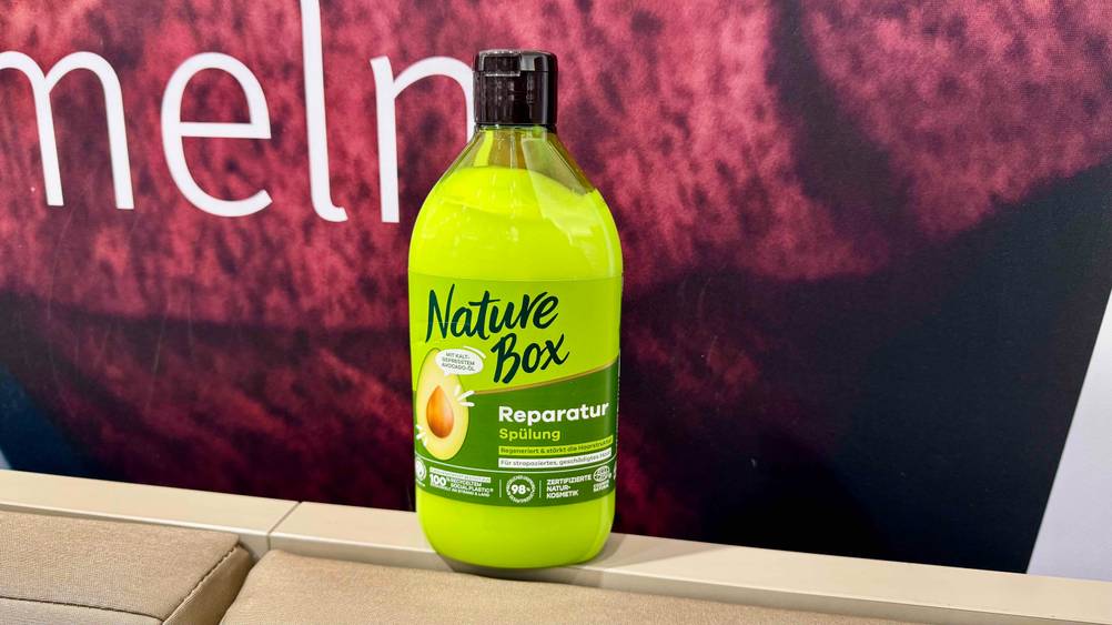 Eine Flasche der getesteten Nature-Box-Spülung vor einem roten Plakat.
