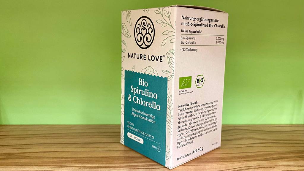 Spirulina-Chlorella-Test: eine Verpackung mit dem Bioprodukt von Nature Love steht vor einer hellgrünen Wand.