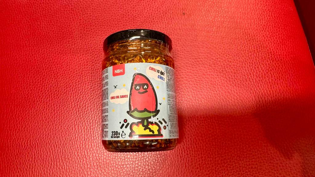 Chiliöl-Test: Ein 230-g-Glas mit Schraubverschluß liegt auf einer roten Oberfläche.
