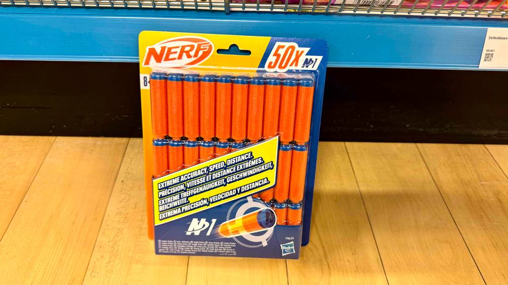 Vor einem Verkaufsregal auf dem Boden befindet sich eine transparente Verpackung der getesteten Nerf-Pfeile.